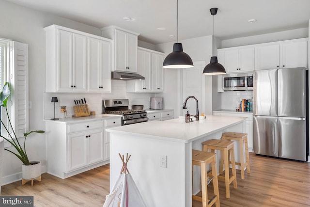 kitchen with white cabinets, an island with sink, stainless steel appliances, and decorative backsplash