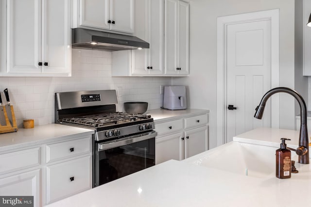 kitchen with stainless steel gas range oven, tasteful backsplash, sink, and white cabinets