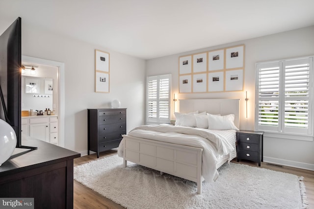 bedroom featuring ensuite bath, dark hardwood / wood-style floors, and multiple windows