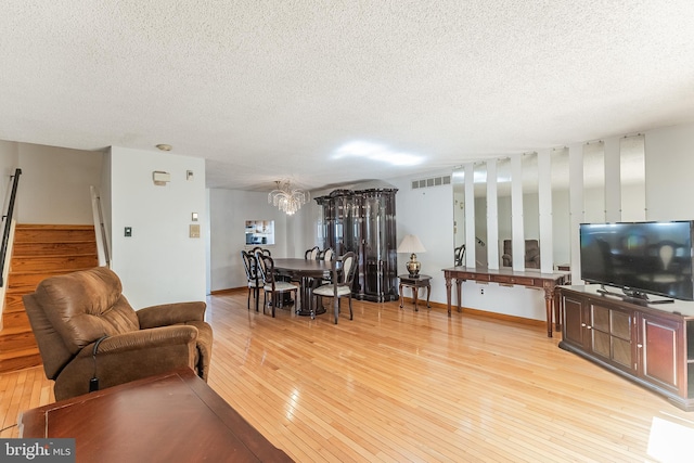 living room featuring light hardwood / wood-style floors, an inviting chandelier, and a textured ceiling