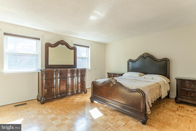 bedroom with a textured ceiling and light parquet floors