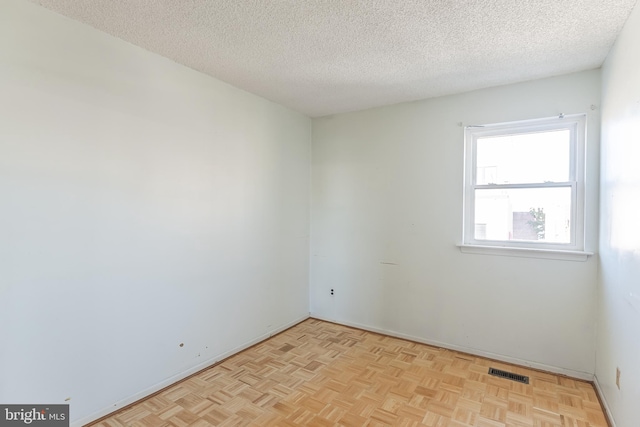 spare room featuring a textured ceiling and light parquet floors