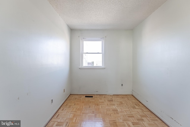 unfurnished room featuring light parquet flooring and a textured ceiling