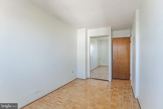 unfurnished bedroom featuring light parquet flooring and a textured ceiling