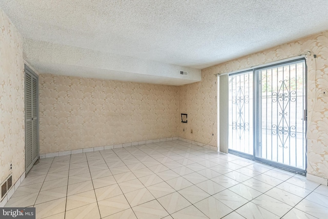 tiled spare room with a textured ceiling