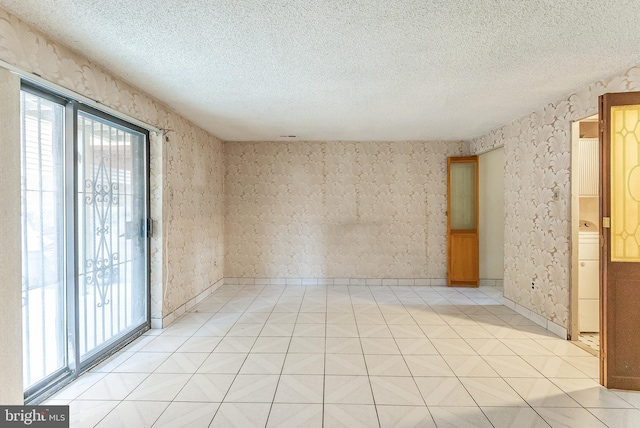 empty room with light tile patterned flooring, washer / clothes dryer, and a textured ceiling