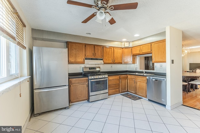 kitchen with light hardwood / wood-style floors, ceiling fan, sink, appliances with stainless steel finishes, and a textured ceiling