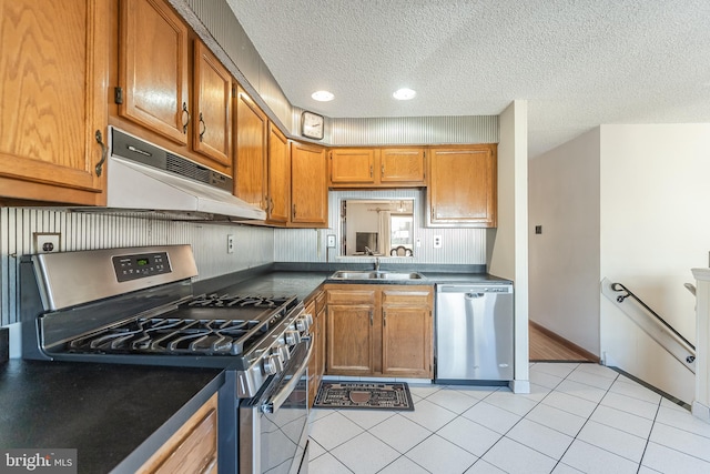 kitchen featuring stainless steel appliances, sink, light tile patterned floors, and a textured ceiling