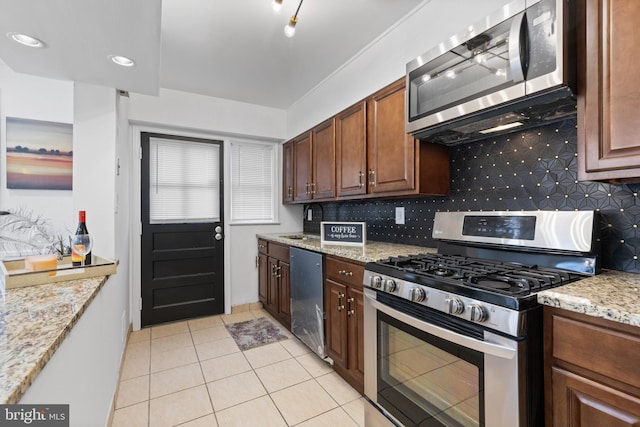 kitchen featuring decorative backsplash, light tile patterned floors, light stone countertops, and appliances with stainless steel finishes