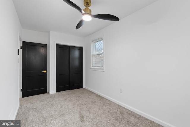 unfurnished bedroom featuring ceiling fan, light colored carpet, and a closet