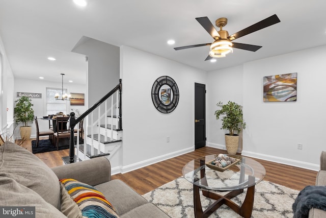 living room featuring ceiling fan with notable chandelier and hardwood / wood-style flooring