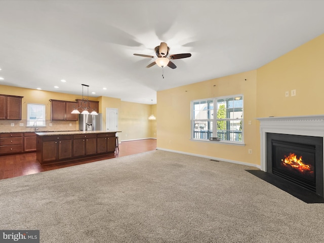 unfurnished living room featuring sink, dark colored carpet, and ceiling fan