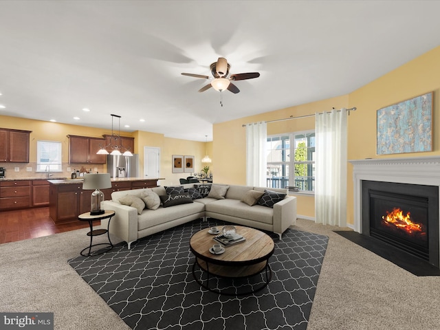 carpeted living room featuring sink and ceiling fan