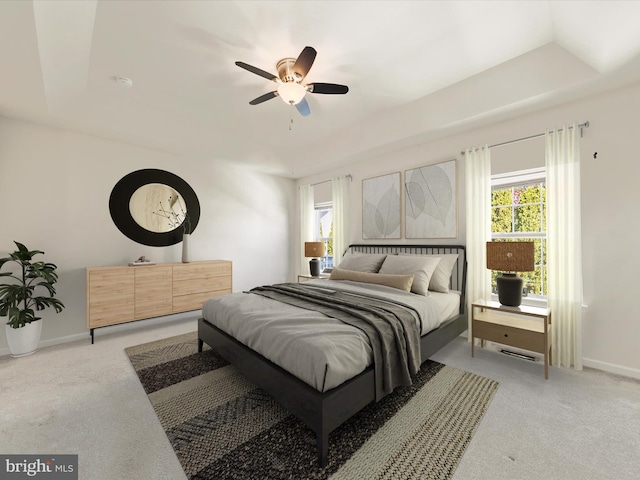 carpeted bedroom with ceiling fan and a tray ceiling