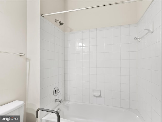 bathroom with toilet and tiled shower / bath