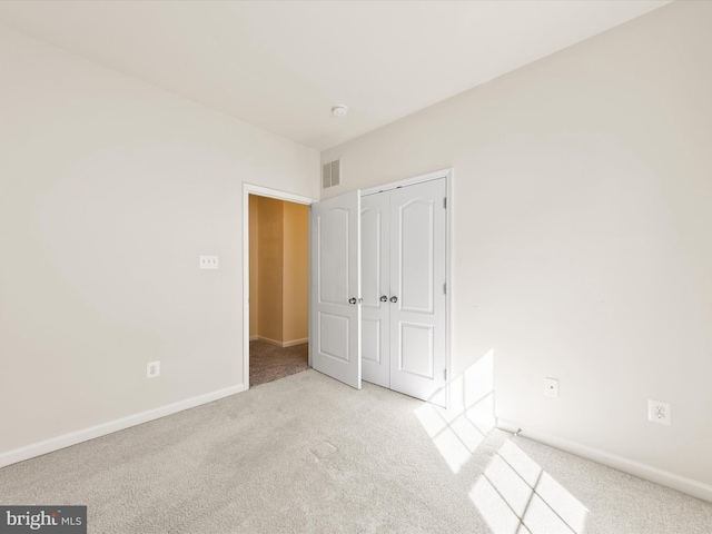 unfurnished bedroom featuring light colored carpet and a closet