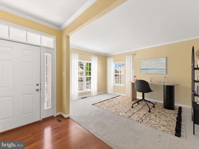 foyer with built in desk, wood-type flooring, and ornamental molding