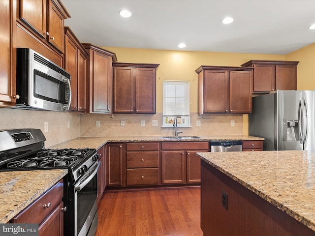 kitchen with dark hardwood / wood-style floors, sink, appliances with stainless steel finishes, light stone counters, and tasteful backsplash