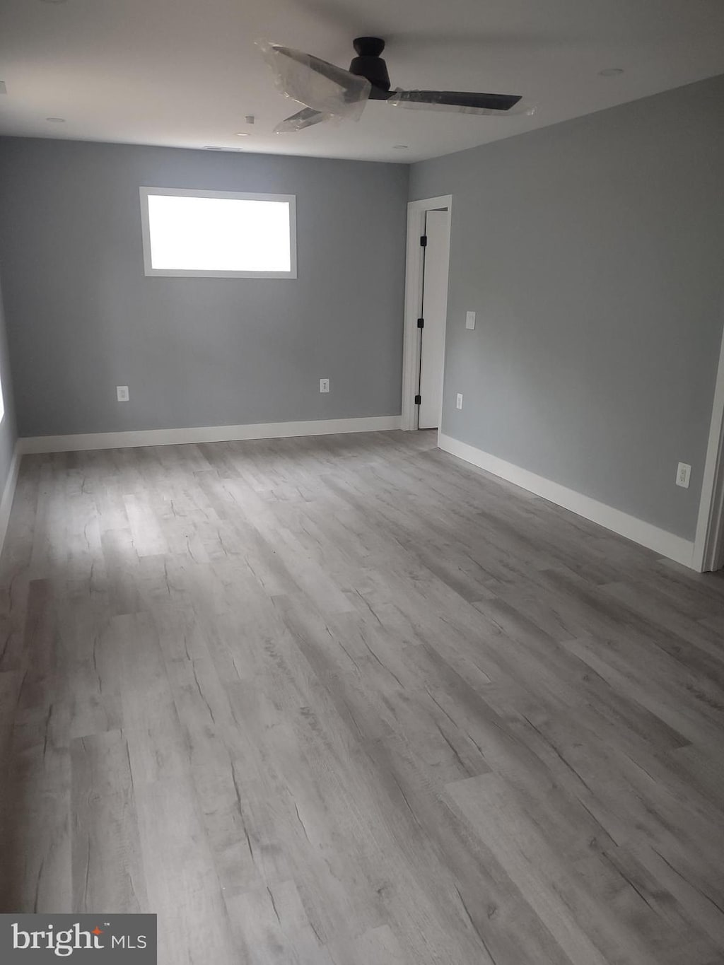 spare room featuring wood finished floors, baseboards, and ceiling fan