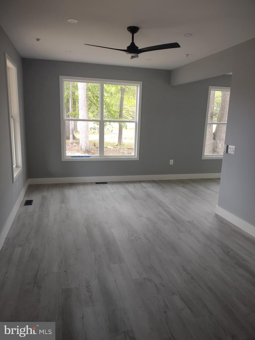 spare room with a wealth of natural light, a ceiling fan, visible vents, and baseboards
