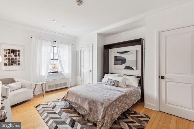 bedroom featuring light hardwood / wood-style floors, crown molding, and radiator