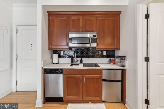 kitchen featuring ornamental molding, stainless steel appliances, light wood-type flooring, and tasteful backsplash