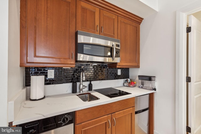 kitchen featuring appliances with stainless steel finishes, tasteful backsplash, sink, and light stone counters