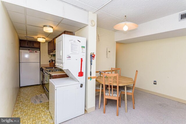 kitchen featuring stacked washer / dryer, light carpet, and white refrigerator