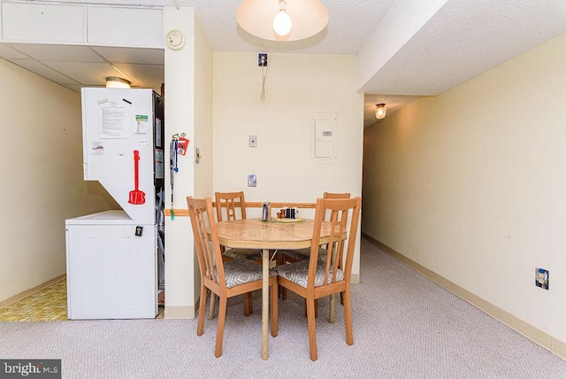 dining area with light carpet, electric panel, and stacked washer / dryer