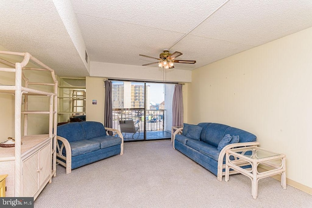living area featuring light colored carpet, a textured ceiling, ceiling fan, and visible vents