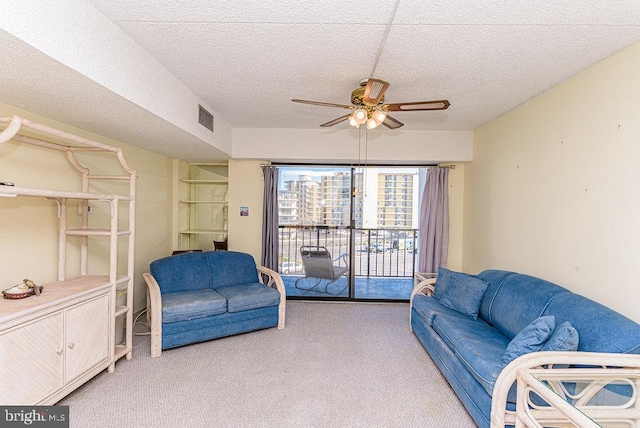 living room featuring a textured ceiling, light colored carpet, and ceiling fan