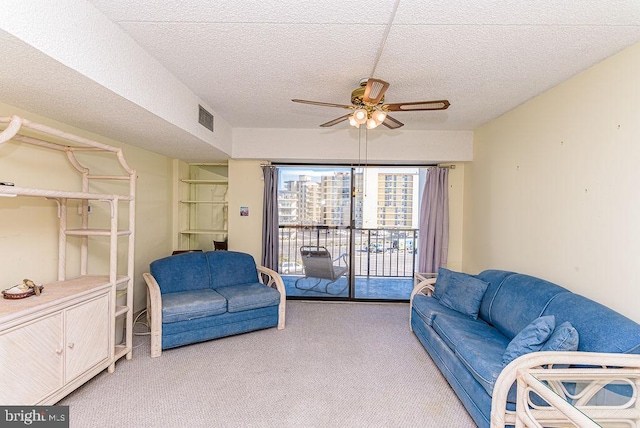 living area featuring a textured ceiling, visible vents, ceiling fan, and light carpet