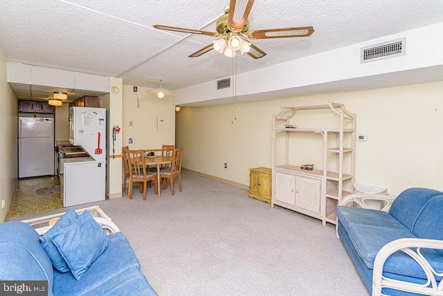 living area featuring light colored carpet, a textured ceiling, visible vents, and ceiling fan