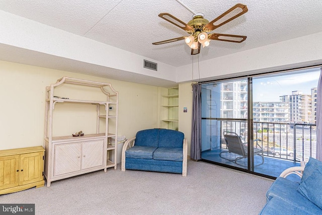 interior space featuring carpet flooring, a textured ceiling, visible vents, and a ceiling fan