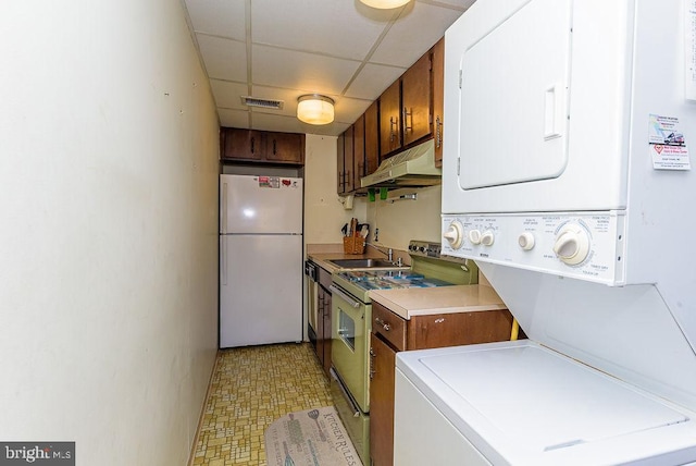 kitchen with sink, a drop ceiling, stacked washer / dryer, electric range, and white refrigerator