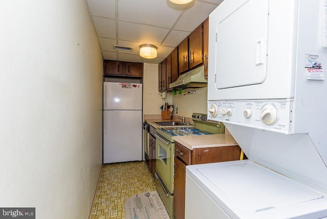 kitchen featuring freestanding refrigerator, stacked washer / drying machine, visible vents, under cabinet range hood, and electric range