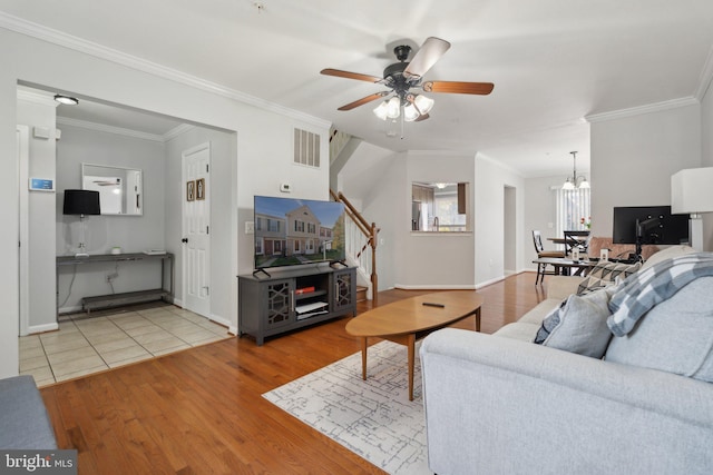 living room with light hardwood / wood-style flooring, ornamental molding, and ceiling fan with notable chandelier