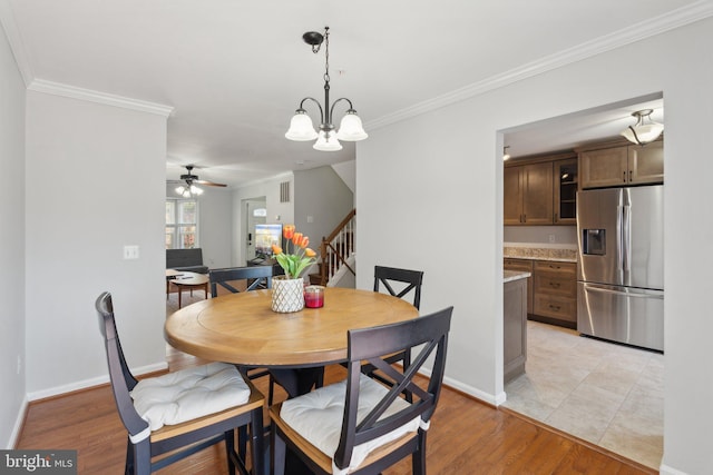 dining space featuring light hardwood / wood-style flooring, ceiling fan with notable chandelier, and crown molding