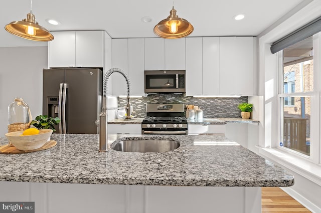 kitchen with white cabinetry, decorative light fixtures, stainless steel appliances, and backsplash