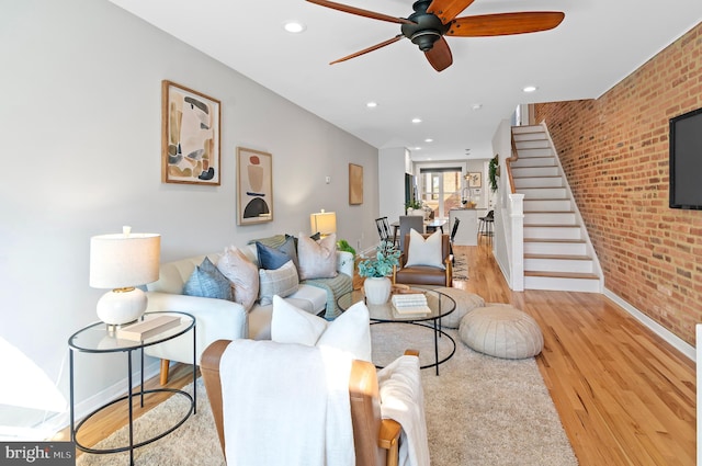 living room with brick wall, light hardwood / wood-style flooring, and ceiling fan