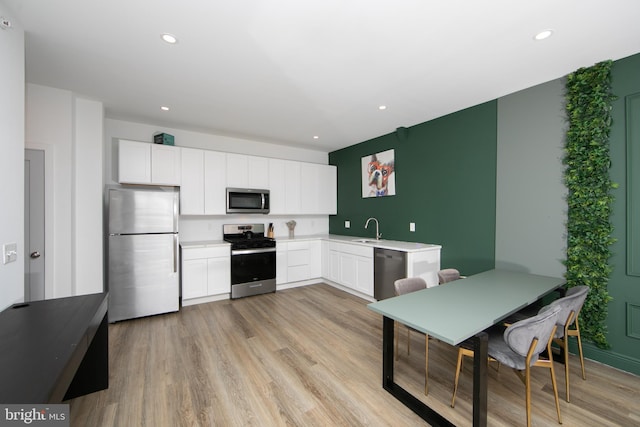 kitchen featuring white cabinetry, stainless steel appliances, sink, and light wood-type flooring