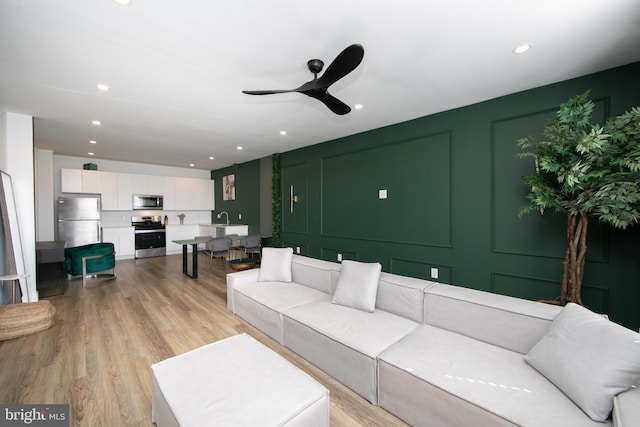 living room with light hardwood / wood-style floors, sink, and ceiling fan