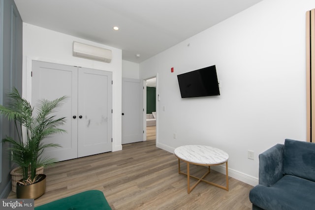 living area with light hardwood / wood-style flooring and a wall unit AC