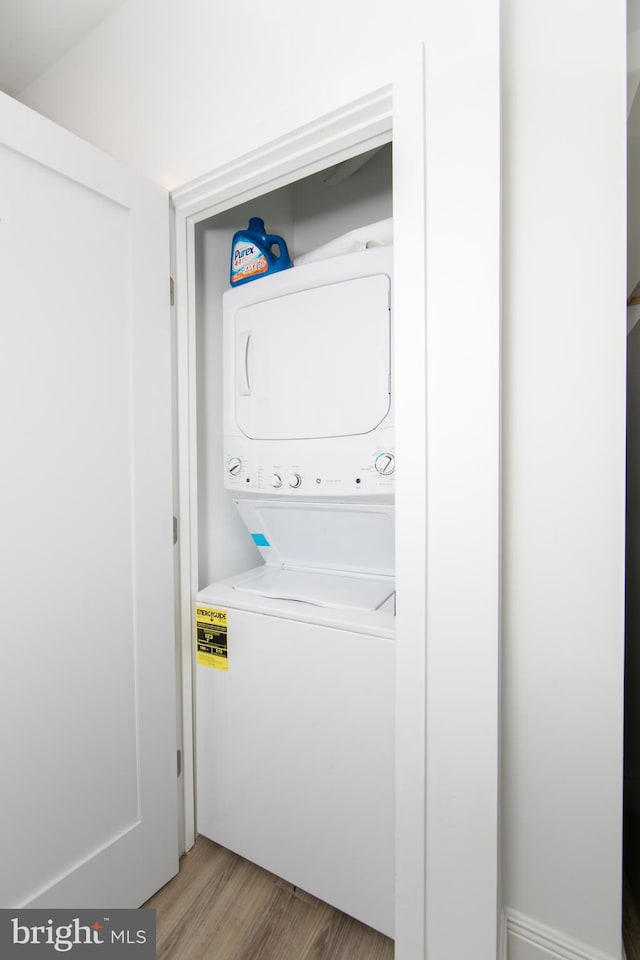 laundry room with light hardwood / wood-style floors and stacked washer and dryer