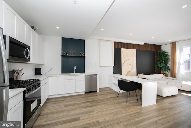 kitchen with sink, white cabinetry, light hardwood / wood-style flooring, and stainless steel appliances