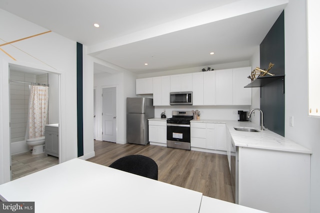 kitchen with sink, appliances with stainless steel finishes, hardwood / wood-style flooring, and white cabinets