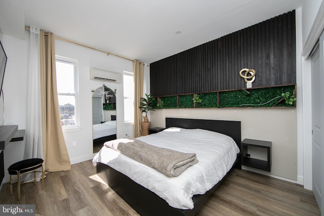 bedroom with wood-type flooring and a wall unit AC