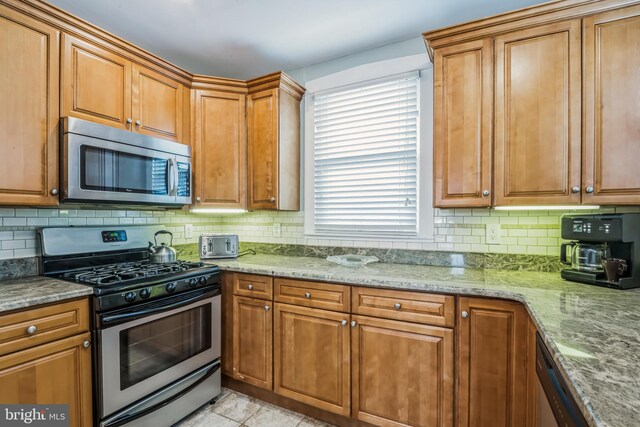 kitchen with light stone countertops, stainless steel appliances, and tasteful backsplash