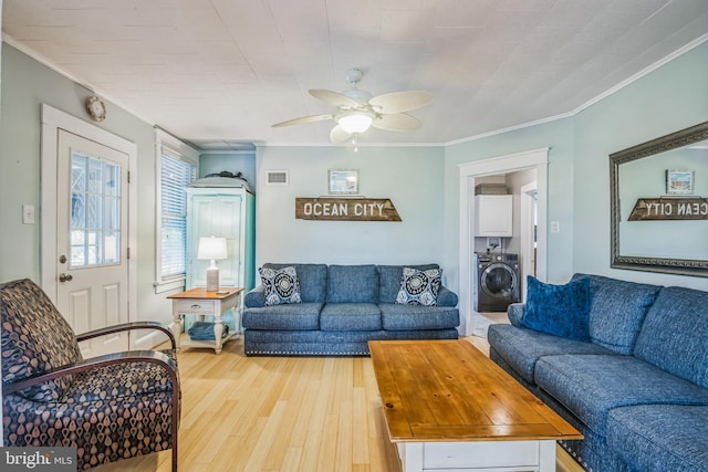 living room with washer / dryer, ornamental molding, light hardwood / wood-style flooring, and ceiling fan