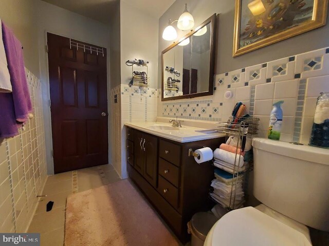 bathroom with vanity, tile walls, and toilet